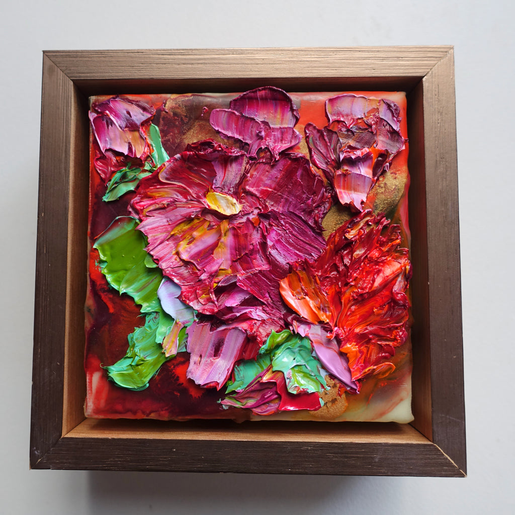 A cut oil painting with tones of hot pink, red and green, framed in light oak with gold face