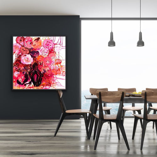 A mass of red and pink blooms in a black vase against a dark grey wall.