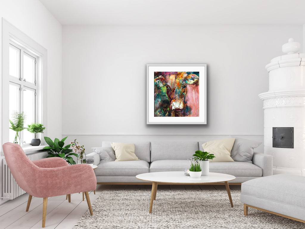 A gorgeous print of Dairy Queen the cow. Set against a muted, multi coloured background in a white frame.