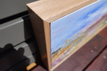 Load image into Gallery viewer, Abstract painting of a field in shades of pink, orange and yellow against a blue sky. Close-up of frame.
