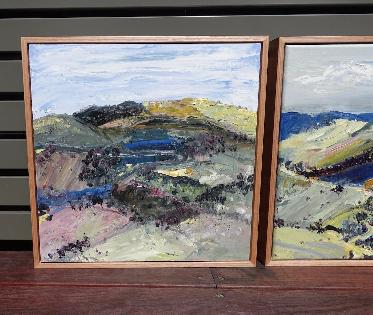 Abstract landscape with the countryside painted in yellow, pink, green and blue. Alongside a matching painting.