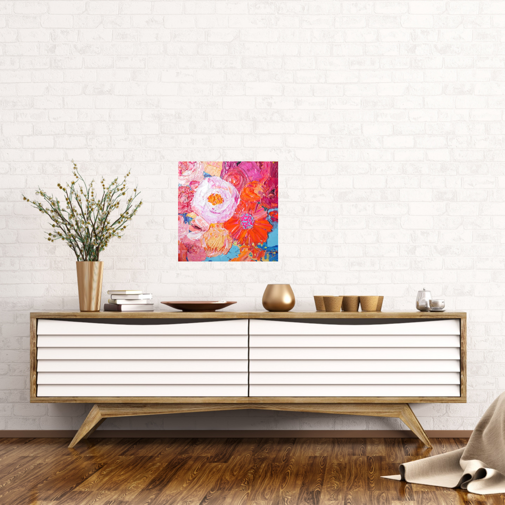 Petal is an original painting of a mass of pale pink, hot pink, orange and soft yellow flowers on a light blue background. Acrylic on canvas, 39cm x 39cm. Shown in situ against a white brick wall above a white and timber sideboard.