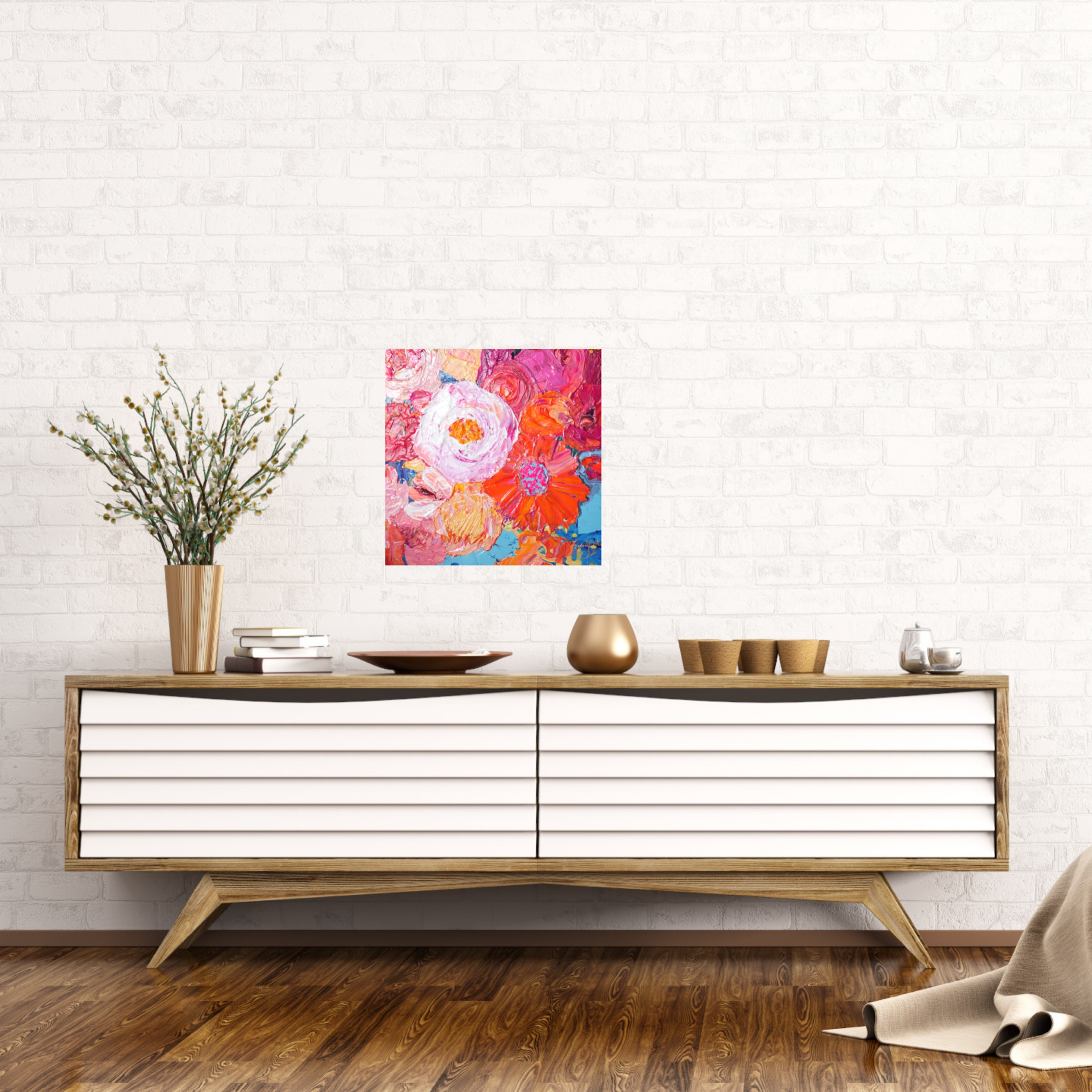 Petal is an original painting of a mass of pale pink, hot pink, orange and soft yellow flowers on a light blue background. Acrylic on canvas, 39cm x 39cm. Shown in situ against a white brick wall above a white and timber sideboard.