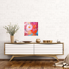 Load image into Gallery viewer, Petal is an original painting of a mass of pale pink, hot pink, orange and soft yellow flowers on a light blue background. Acrylic on canvas, 39cm x 39cm. Shown in situ against a white brick wall above a white and timber sideboard.
