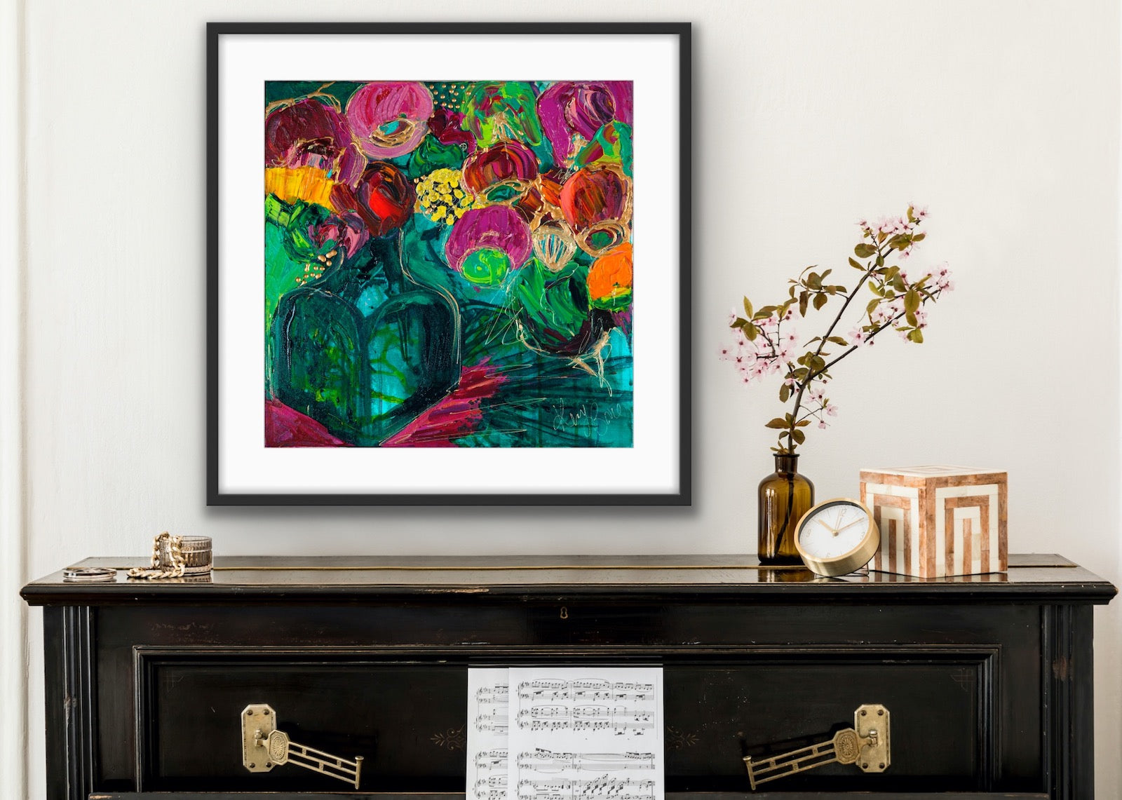 A magnificent bunch of vibrant blooms in a turquoise glass vase against a turquoise, green and magenta background, in a timber frame.