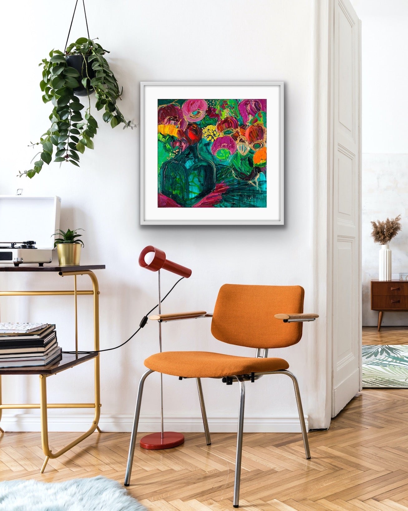 A magnificent bunch of vibrant blooms in a turquoise glass vase against a turquoise, green and magenta background, framed in white timber.