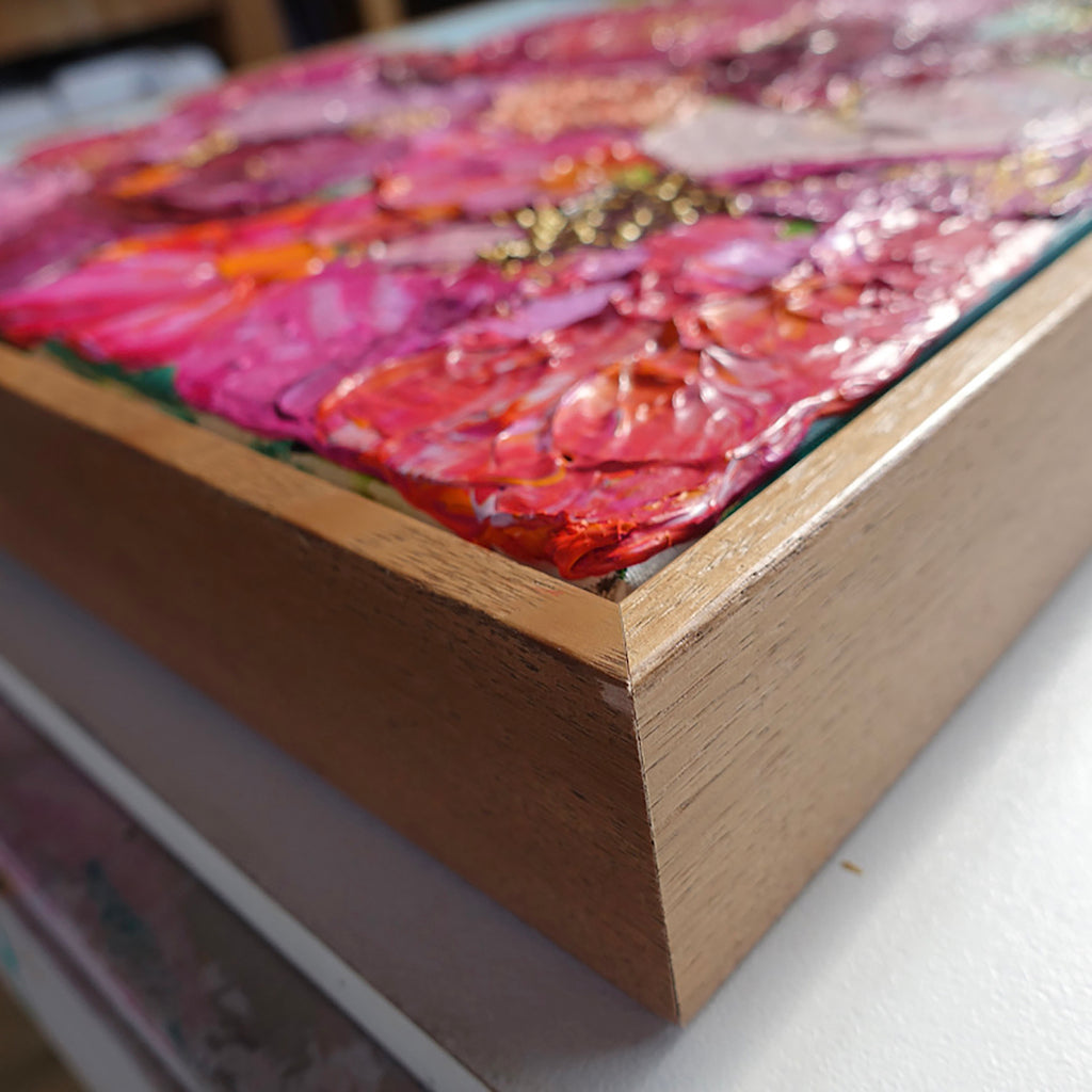 Close up view of an original painting of a gorgeous bunch of florals in all shades of pink, entwined with gold thread on a pale blue background.