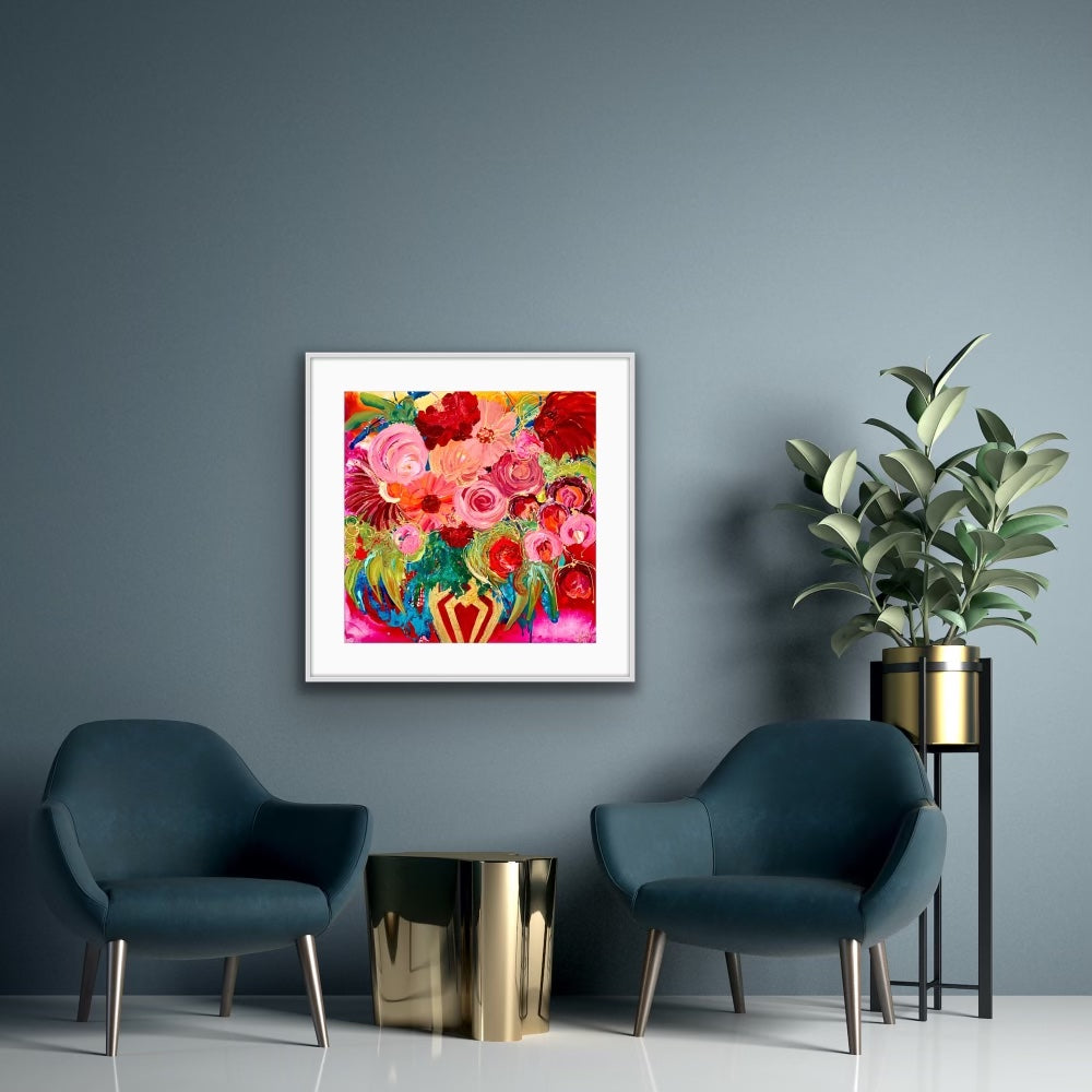 A stunningly beautiful print of a mass of blooms in shades of pink, red outlined in gold, in a gold vase against a hot pink background. Framed in white timber.