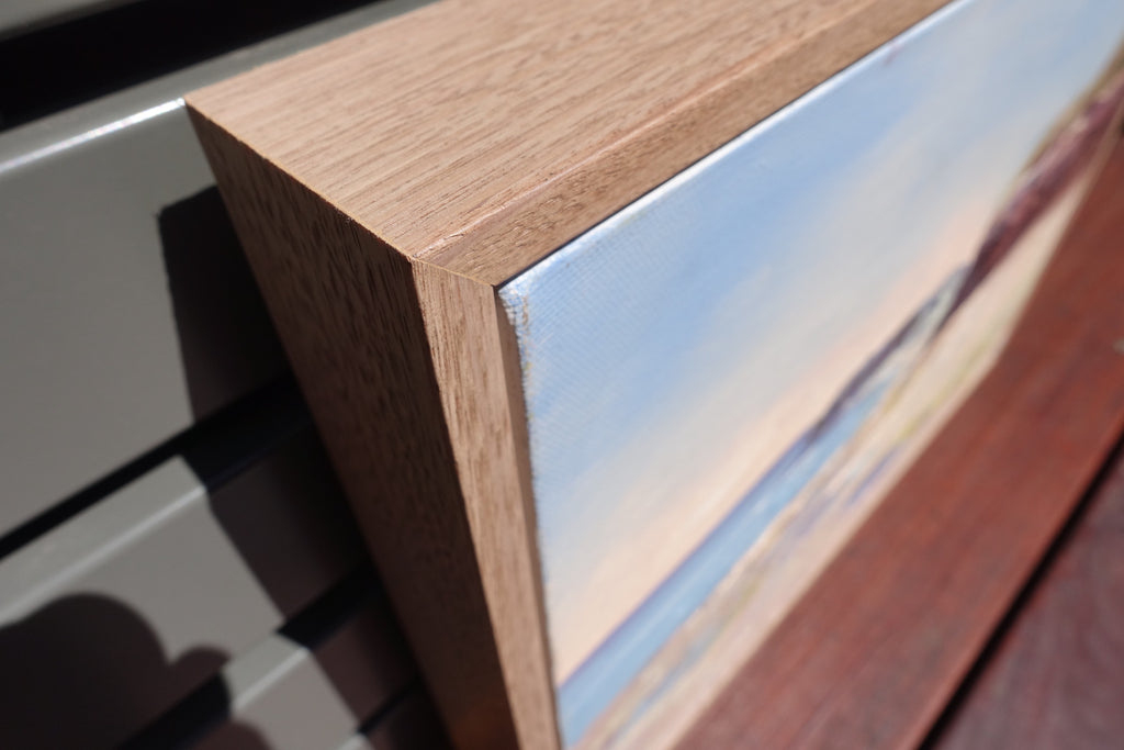 Ocean and rock pools in soft pastel colours with reddish brown cliffs. Close-up of frame.