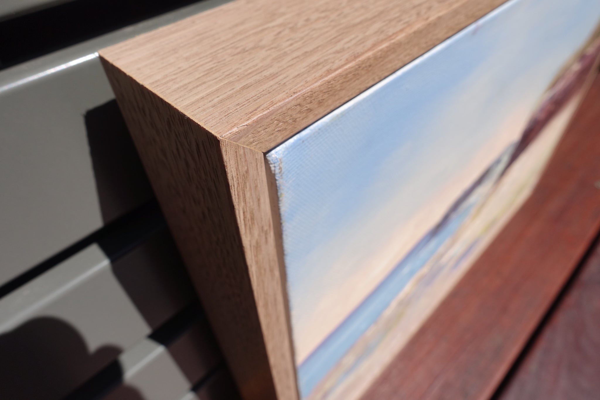 Ocean and rock pools in soft pastel colours with reddish brown cliffs. Close-up of frame.