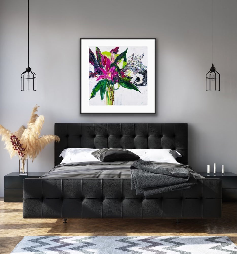 A tall stemmed bloom in shades of violet and plum with greenery in a long, slim glass vase, framed in black.