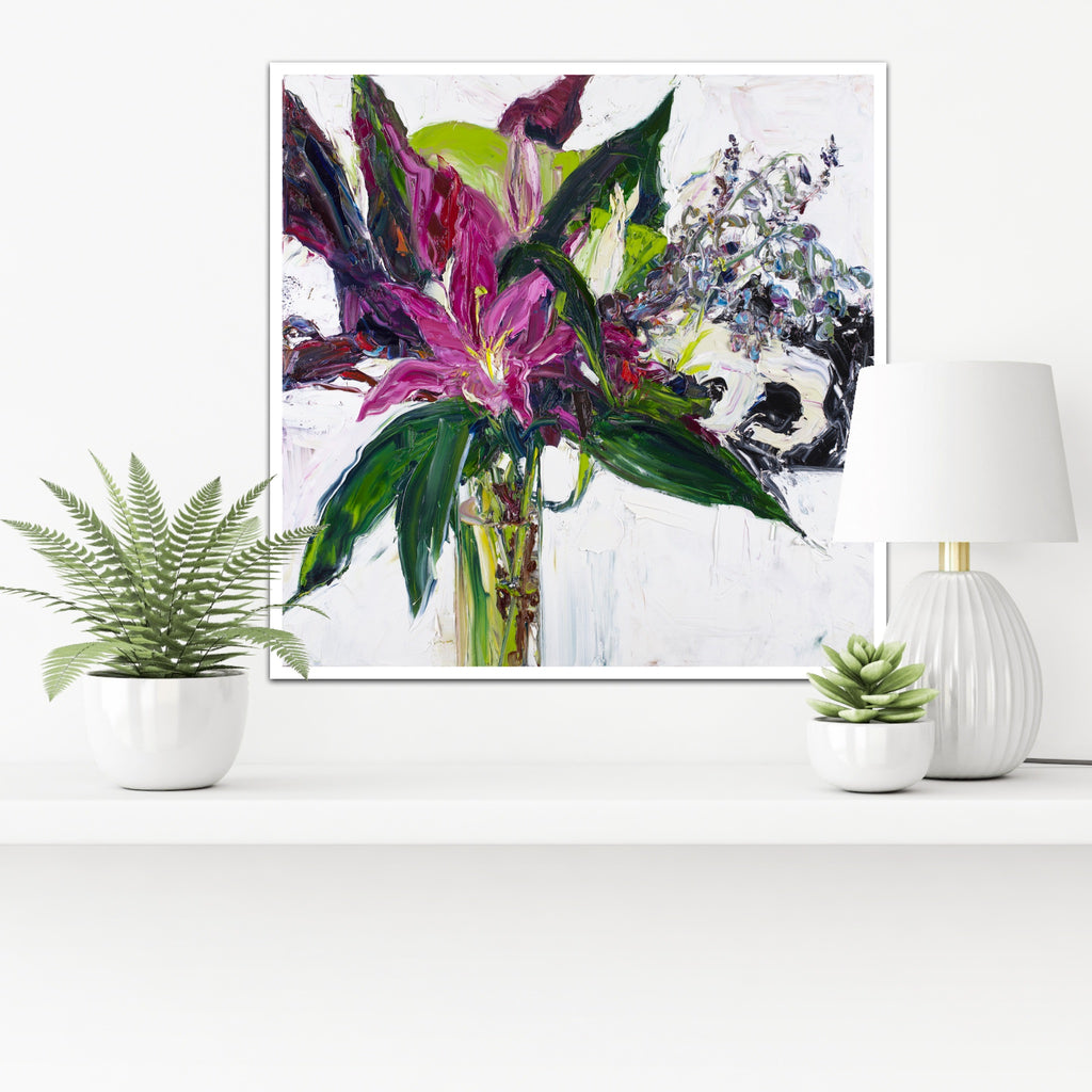 A tall stemmed bloom in shades of violet and plum with greenery in a long, slim glass vase, framed in white timber.